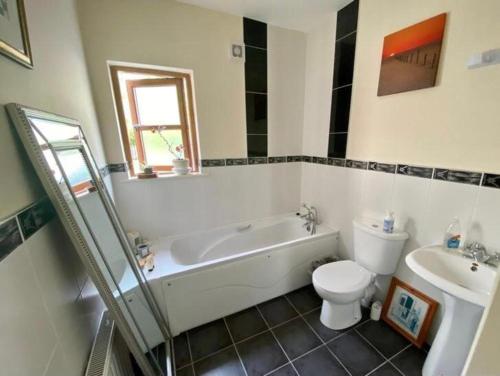 a bathroom with a tub and a toilet and a sink at Kilronan 4 Bed House on castle grounds in Ballyfarnon