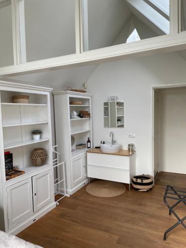 a bathroom with white cabinets and a sink at Prins Heerlijk in Sassenheim