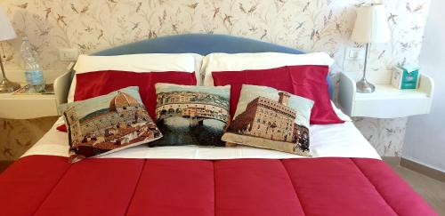 een bed met rode en witte kussens erop bij appartamento pontevecchio in Florence