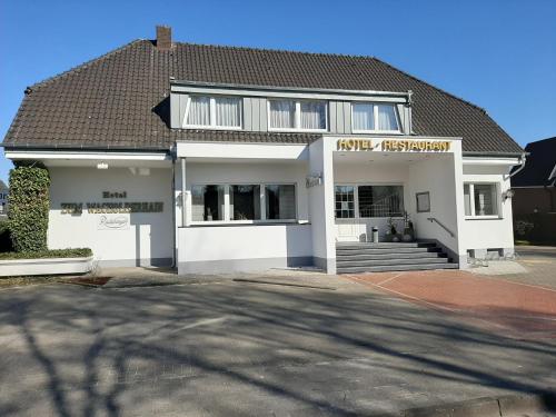 a white house with a sign on the front of it at Hotel Restaurant Zum Wacholderhain in Haselünne