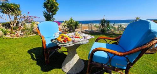 2 Stühle und ein Tisch mit einem Tablett mit Obst in der Unterkunft Luxury Seafront Pool Villa - 3 Stories & Roof floor - All Master Bedrooms in Hurghada