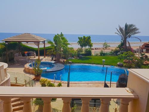 a view from the balcony of a resort with a swimming pool and the beach at Luxury Seafront Pool Villa - 3 Stories & Roof floor - All Master Bedrooms in Hurghada