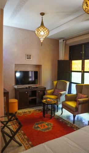 a living room with a couch and chairs and a television at Riad Sultan Suleiman in Marrakech