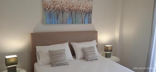 a bedroom with a bed with white pillows and a painting at lemonishouse by the sea 1 in Nea Skioni