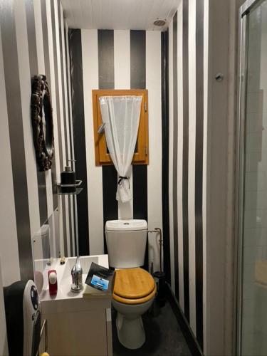 La salle de bains est pourvue de toilettes et d'un siège en bois. dans l'établissement Les feuilles jaunes, à Chantenay-Saint-Imbert