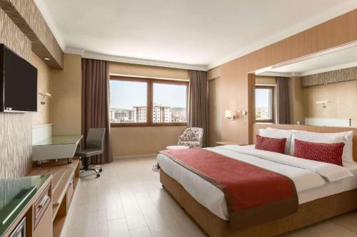 Habitación de hotel con cama grande y TV en Ramada Usak, en Uşak