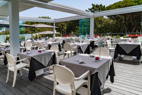 a restaurant with white tables and chairs on a deck at Raffaello Hotel & Mooka Restaurant in Senigallia