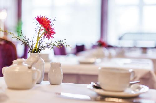 un tavolo con un vaso con un fiore e una tazza di Trans World Hotel Columbus a Seligenstadt