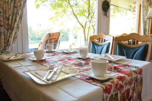 uma mesa com uma toalha de mesa numa mesa com cadeiras e uma janela em Pension am Hardausee em Suderburg