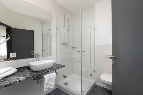 a white bathroom with a sink and a shower at Zur Blume Hotel & Restaurant Efringen-Kirchen bei Basel in Efringen-Kirchen