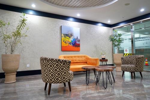 an office lobby with an orange couch and chairs at Apartemen MATARAM CITY YUDHISTIRA TOWER YOGYAKARTA in Kejayan