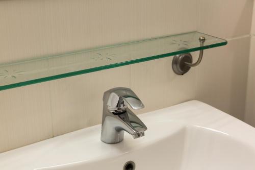 a bathroom sink with a faucet and a green shelf at The Originals Access, Hôtel La Dousseine, Dreux Nord (Inter-Hotel) in Anet