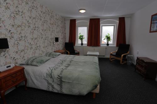 een slaapkamer met een bed en 2 stoelen en ramen bij Haus Stefanie Elvire in Kurort Altenberg