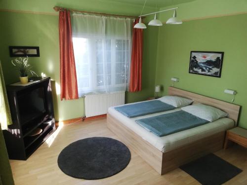 sypialnia z łóżkiem, telewizorem i oknem w obiekcie Kornél Apartman w Siófoku