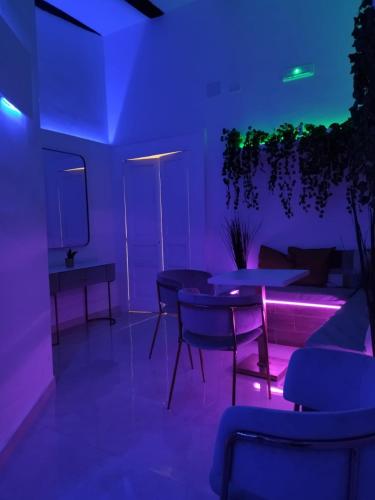 une chambre avec des lumières violettes, des tables et un canapé dans l'établissement RELAIS TORRE GLORIA, à Naples