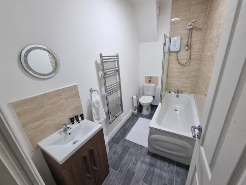 a bathroom with a sink and a toilet and a mirror at *** Well equipped home for a relaxing cosy and luxurious fun stay + Free Parking + Free Fast WiFi *** in Farnley