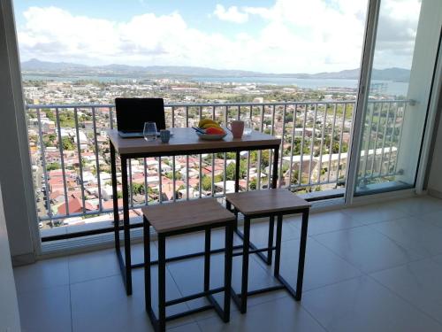 uma mesa e dois bancos em frente a uma grande janela em Bienvenue au 7ème ciel dans le spacieux T3 ! em Fort-de-France