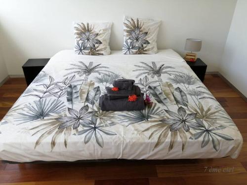 a bed with a white bedspread with palm trees on it at Bienvenue au 7ème ciel dans le spacieux T3 ! in Fort-de-France