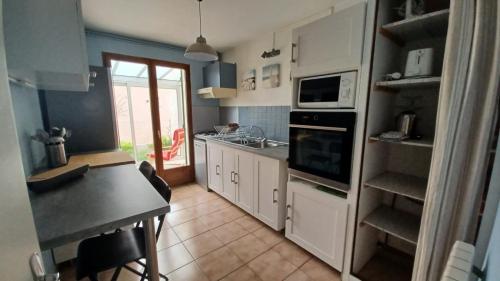 - une cuisine avec des placards blancs, un évier et une table dans l'établissement agréable maison de famille sur gîte echarou, à Sigean