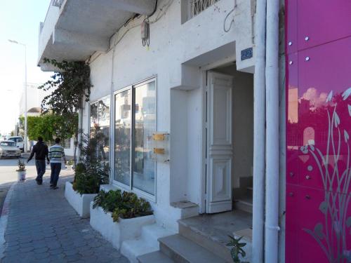 a person walking down a sidewalk in front of a store at la maison de l'architecte in Hammamet