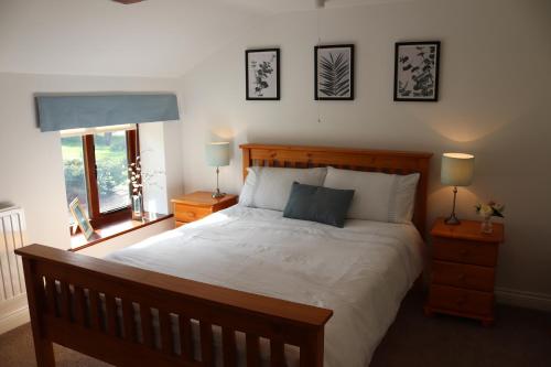 a bedroom with a bed and two lamps and a window at 1 Barge Cottage in Narborough