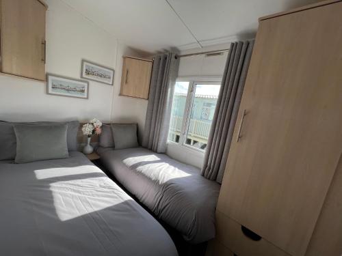 Duas camas num pequeno quarto com uma janela em Forest & beach access Naish park em New Milton