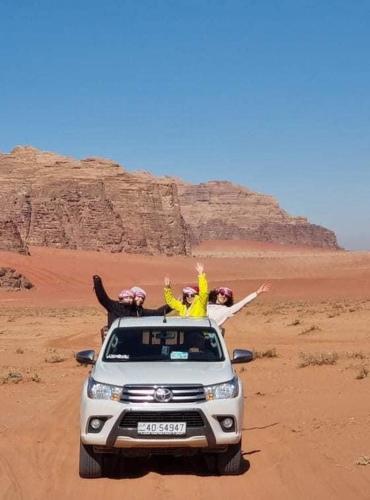a group of people sitting on the roof of a car in the desert at Sand Star Camp in Wadi Rum