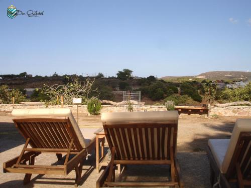 - deux chaises en bois assises sur une terrasse avec vue dans l'établissement DonQuihotel Chalet, à Karvounádhes