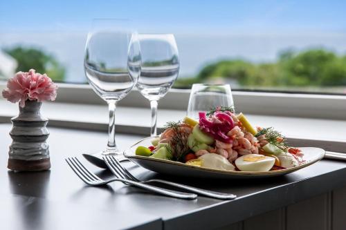 a plate of food on a table with two wine glasses at Hotell och Restaurang Hovs Hallar in Båstad