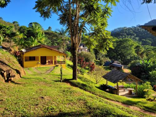 a yellow house in the middle of a green field at Espaço inteiro: Casa de campo nas montanhas in Domingos Martins