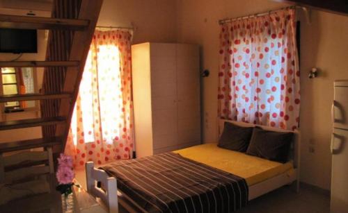 a small bedroom with a bed and curtains and a staircase at Koromilia Villa in Neo Klima