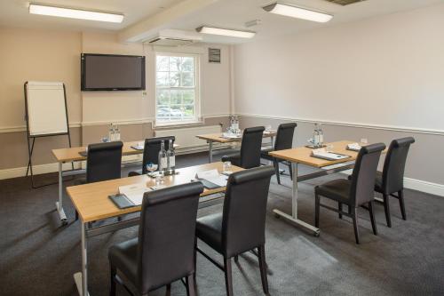 a conference room with tables and chairs and a screen at The Regency Hotel in Solihull