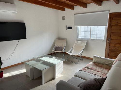 ein Wohnzimmer mit einem Sofa, einem Tisch und einem TV in der Unterkunft Valle de Uco. Departamento 2 habitaciones 4 huéspedes. in Tunuyán