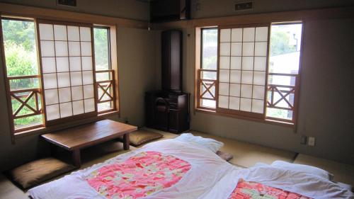 a bedroom with a bed with a table and windows at Ken House Osaka in Takatuki