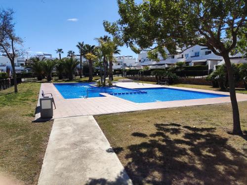 uma piscina num quintal com árvores e casas em Lovely 3 Bedroom Apartment on Golf Resort em Alhama de Múrcia