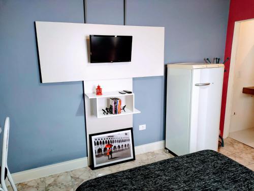 a room with a refrigerator and a tv on a wall at 10 Studios in Sao Paulo