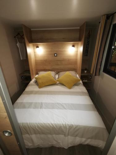 - un lit avec 2 oreillers jaunes dans une petite pièce dans l'établissement Camping la Plage Lot Vallée de la Dordogne Rocamadour, à Meyronne