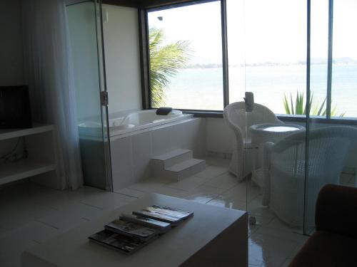 een witte badkamer met een bad, een tafel en een raam bij Barracuda Eco Resort Búzios in Búzios