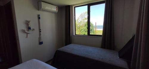 a small room with a window and a bed in a room at Pé na areia Itacimirim in Camacari