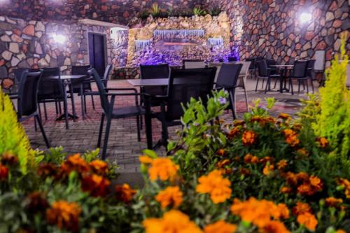 a dining room with tables and chairs and flowers at Hôtel les truites in Imouzzer Kandar