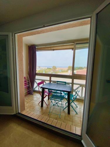Habitación con balcón con mesa y sillas. en Studio Sète vue sur l’étang de Thau en Sète
