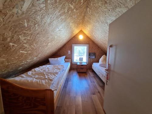 Habitación en el ático con 2 camas y ventana en Ferienhaus direkt am Badesee Bungalow 11 Schönsee, en Urnshausen