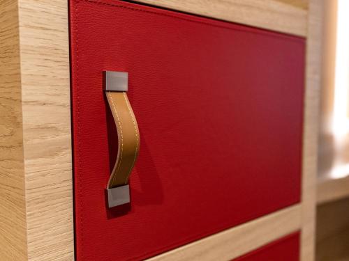 a red door with a gold handle on a wooden drawer at Los Lorentes Hotel Bern City in Bern