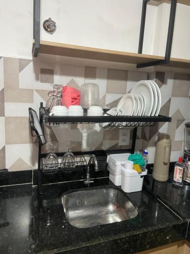 a kitchen counter with a sink and dishes on a shelf at Maraca Beach in Porto De Galinhas