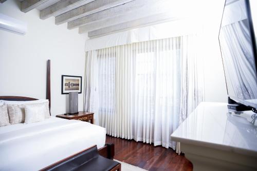 a white bedroom with a bed and a television at Hotel Casa Blanca 7 in San Miguel de Allende