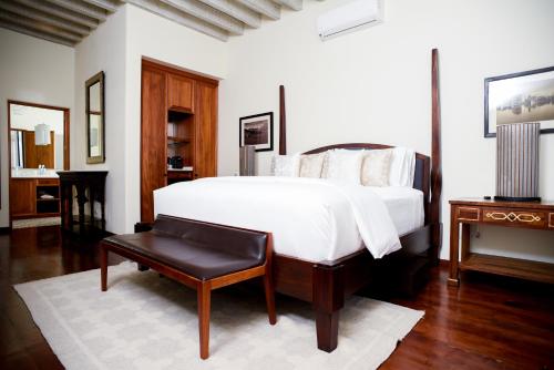 a bedroom with a large white bed and a stool at Hotel Casa Blanca 7 in San Miguel de Allende
