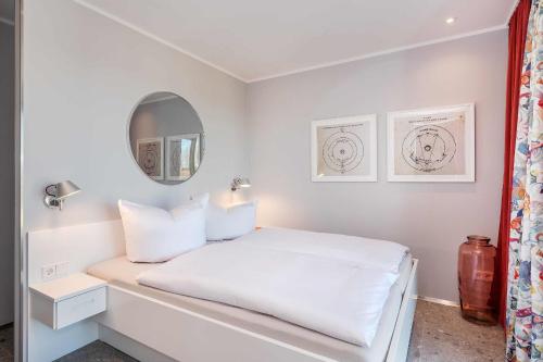 Dormitorio blanco con cama blanca y espejo en Lobster, en Lubmin