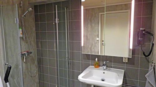 a bathroom with a sink and a shower with a mirror at Bakkegata - Blue House Dormitory in Odda