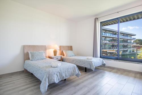 a bedroom with two beds and a large window at Appartement Luxueux dans un site Exceptionnelle Vilamoura in Vilamoura