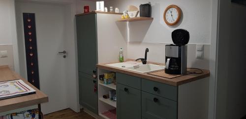 eine Küche mit einem Waschbecken und einer Uhr an der Wand in der Unterkunft Ferienwohnung MAI in Glauchau